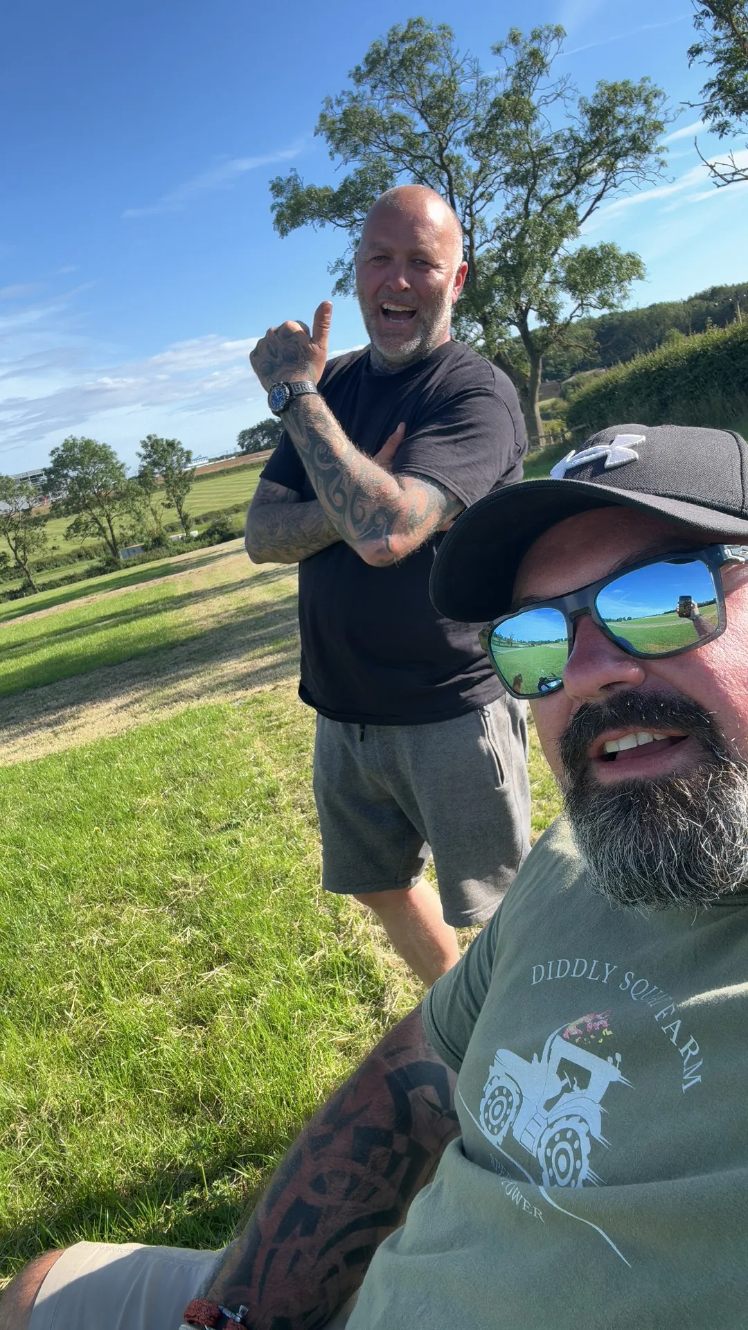 Two visitors smiling on the campsite hillside