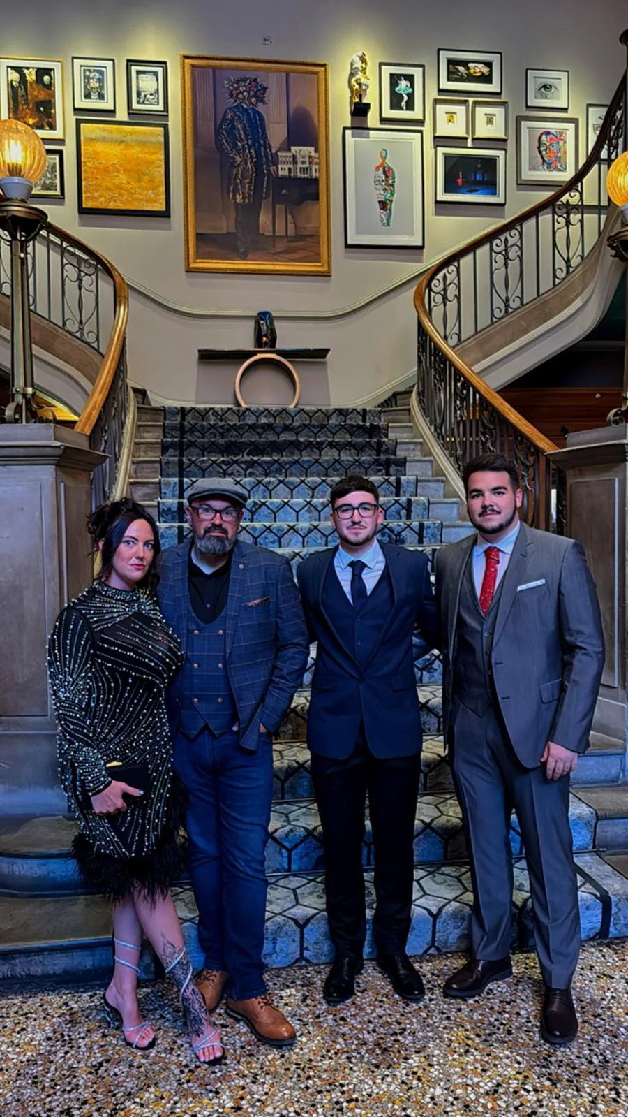 Four team members dressed formally on a staircase