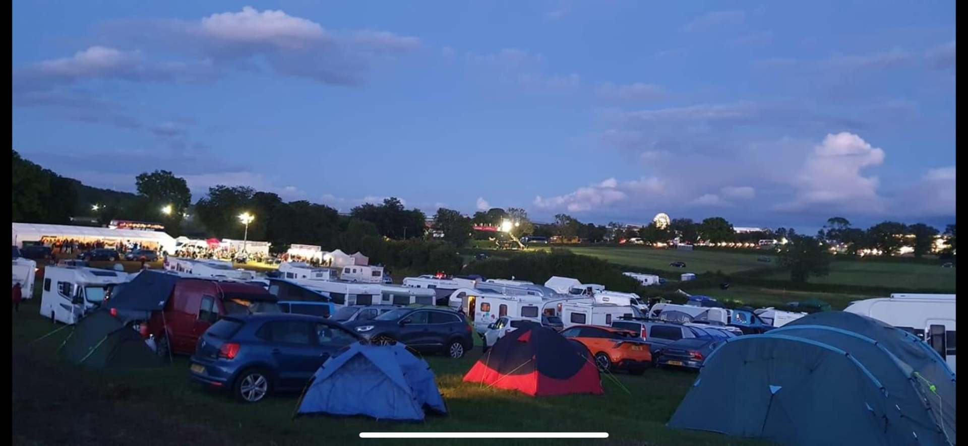 Campsite at dusk with warm evening light over tents and caravans