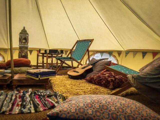 Spacious bell tent interior with double bed, deckchairs and full furnishings