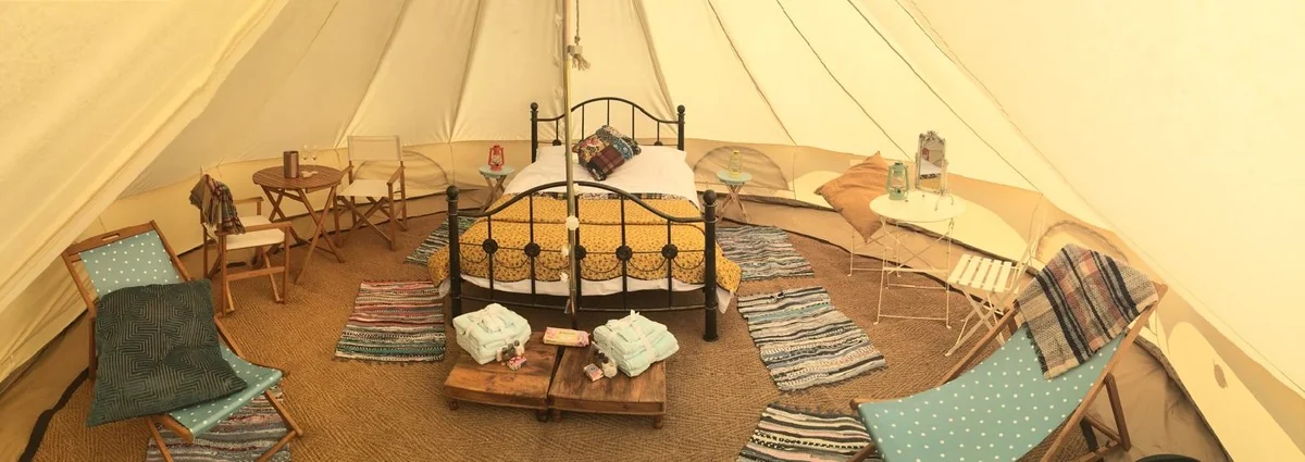 Bell tents glowing with fairy lights under moonlit sky