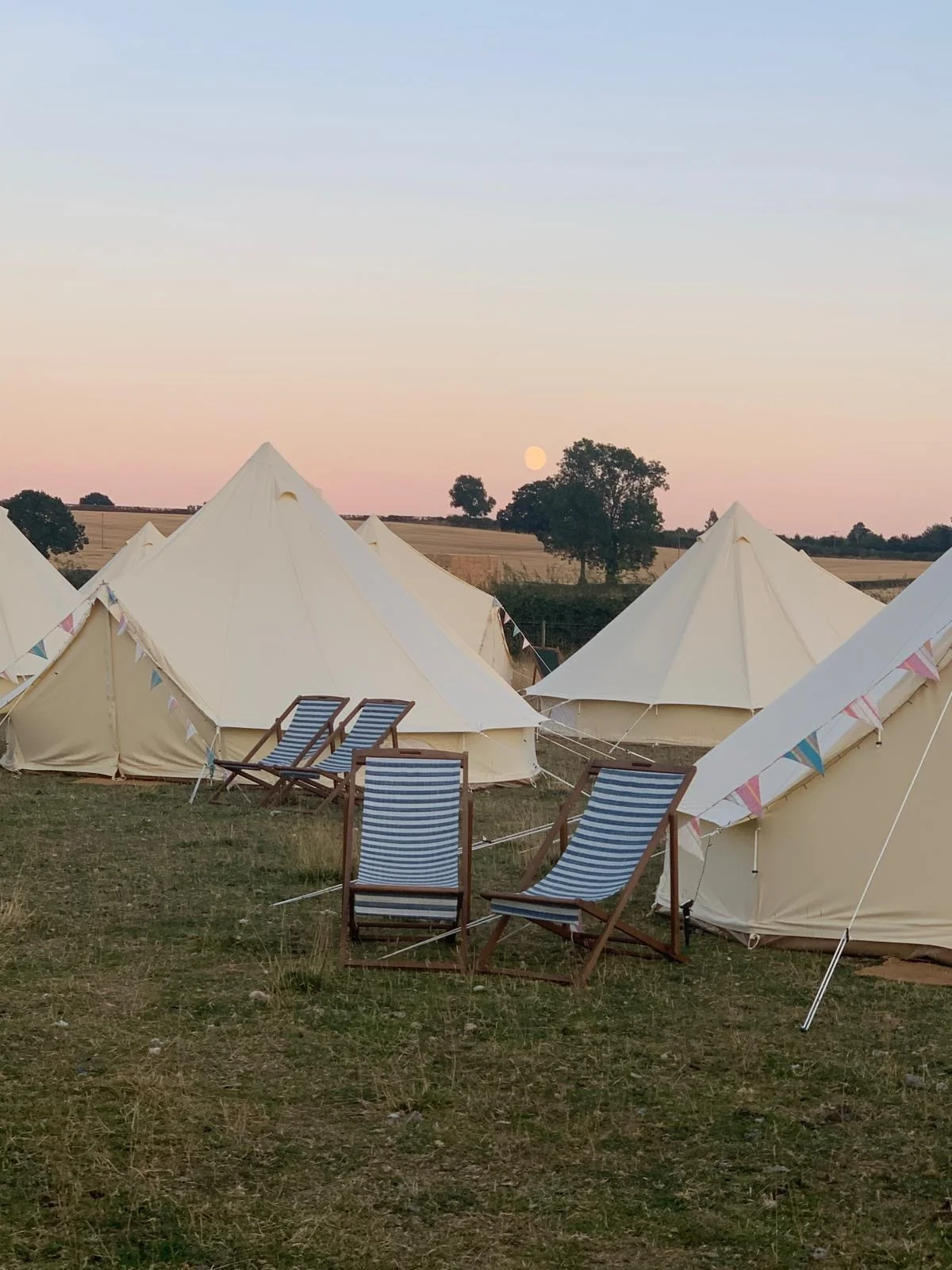 Bell tents at golden hour with deckchairs and sunset views