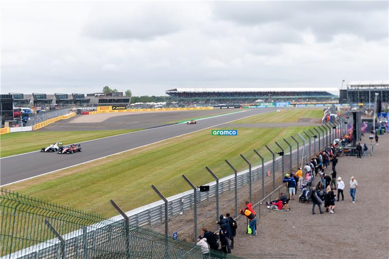 Fans watching Formula 1 cars race past on the Silverstone Circuit during British Grand Prix weekend