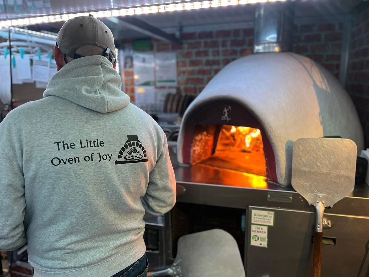 Pizza chef preparing pizza in wood-fired oven