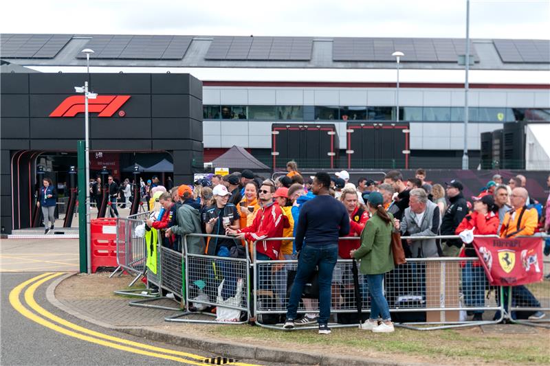 Formula 1 fans waiting at paddock entrance with F1 logo visible at Silverstone